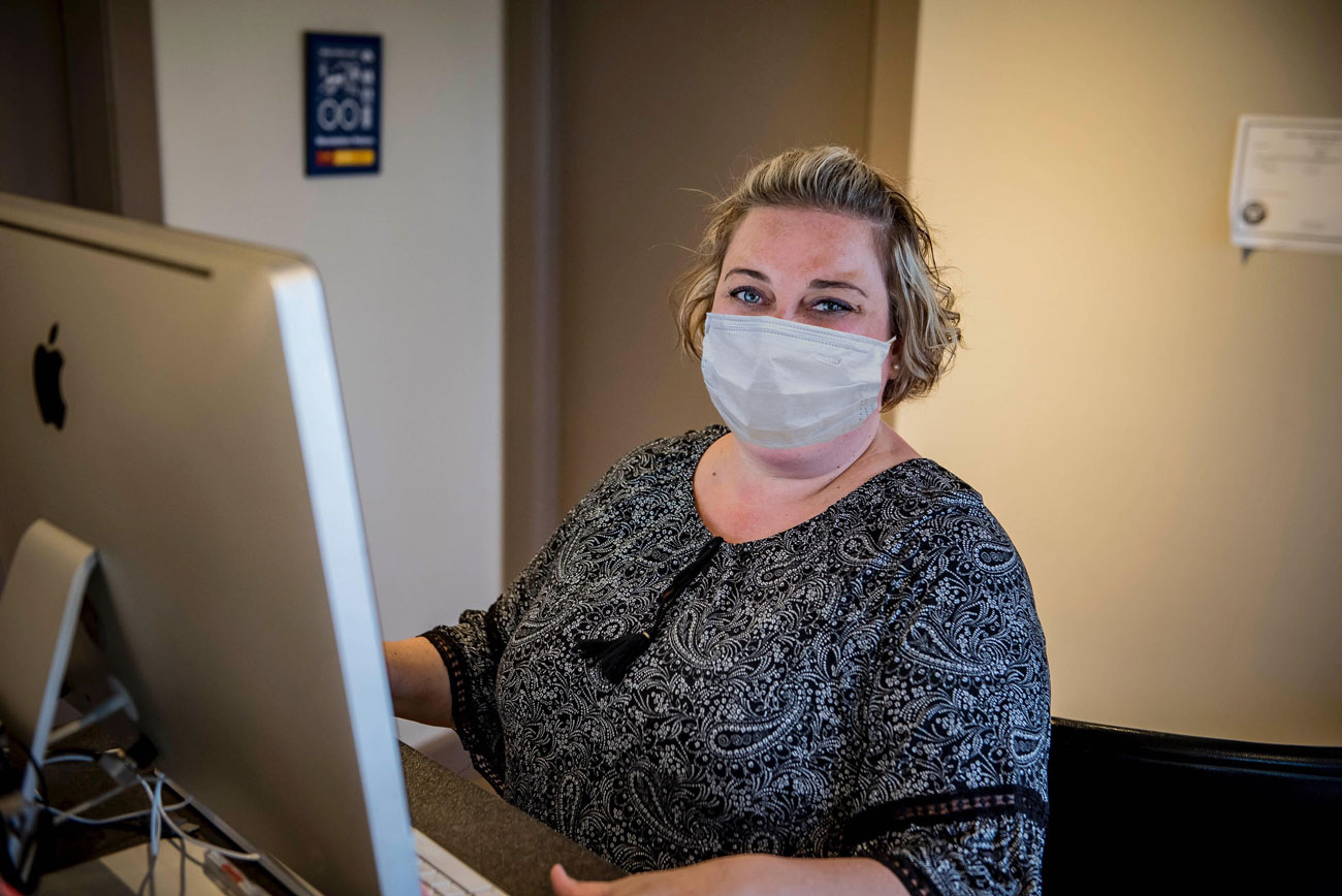Woman wearing mask at the front desk of mechanic shop